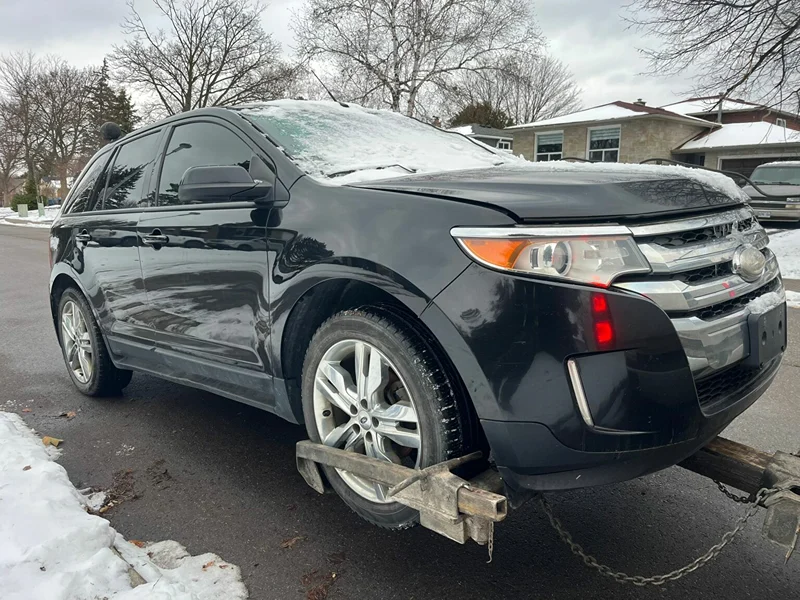 Damaged SUV hooked up to a tow truck for scrap car removal in Hamilton, Ontario